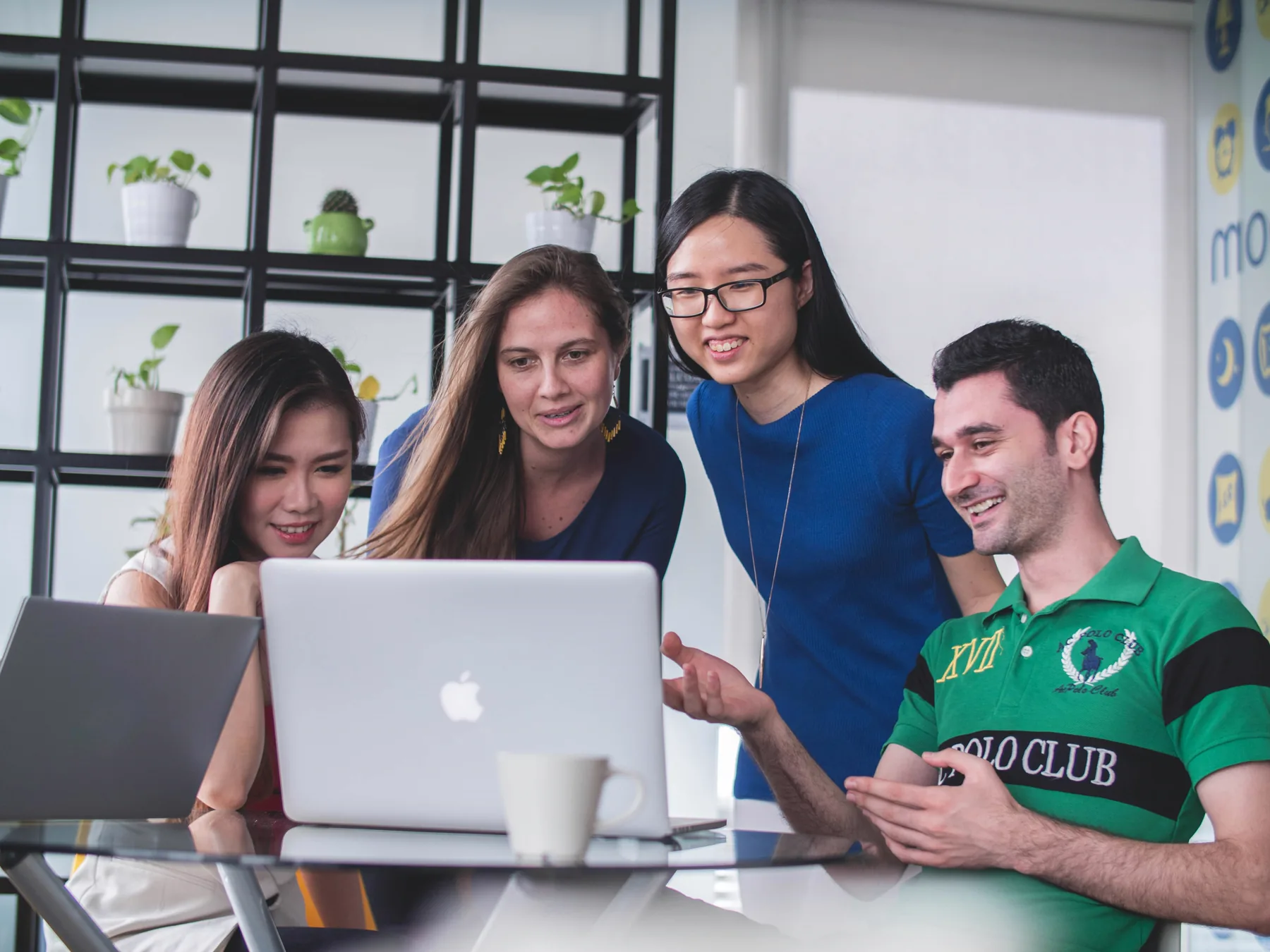 A diverse group collaborates around a laptop.