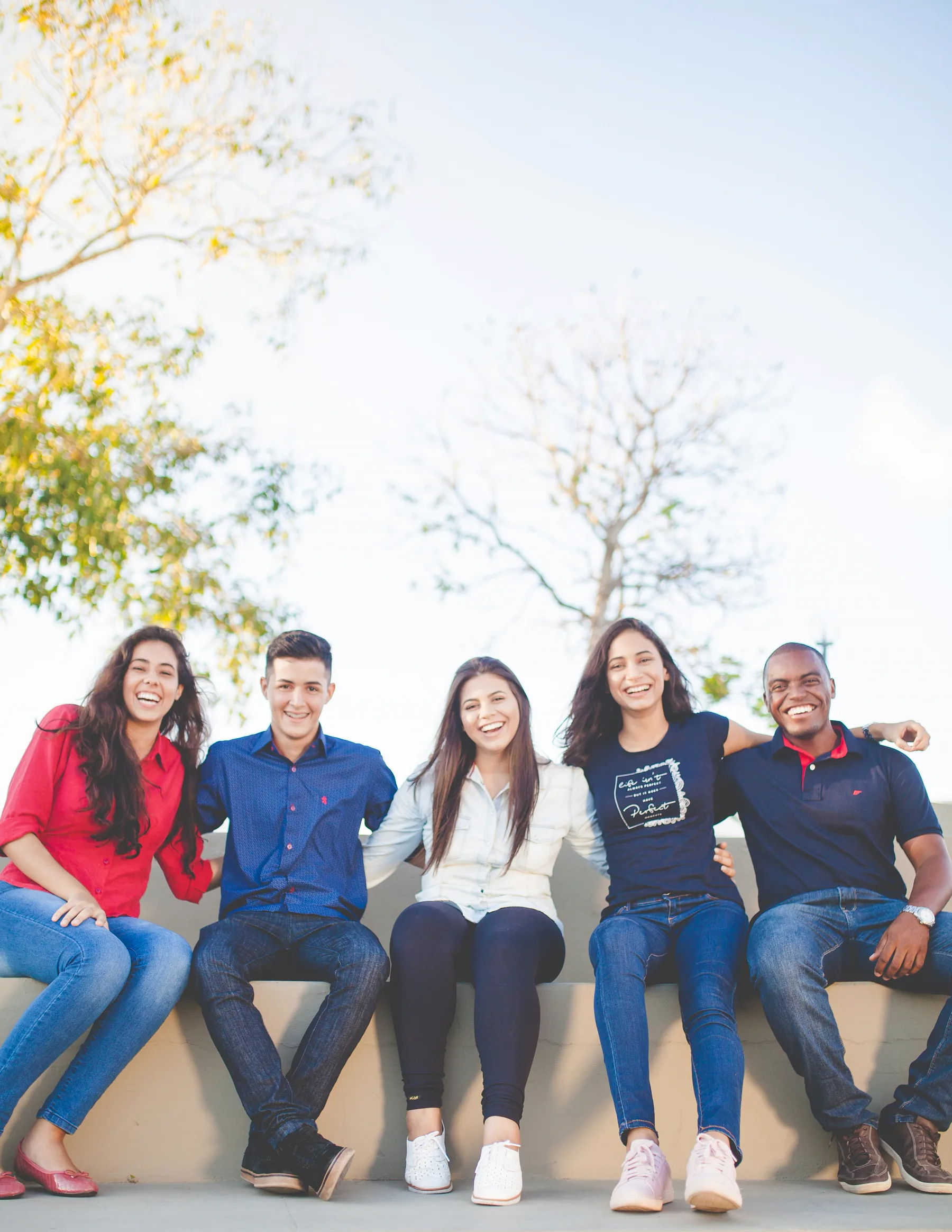 Five friends sit together outdoors.