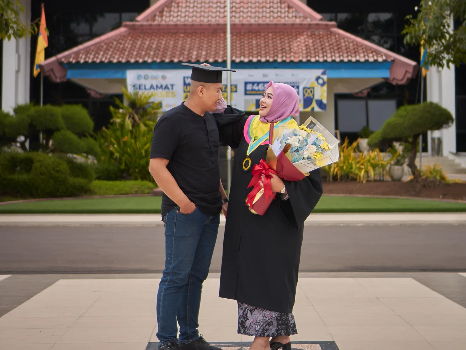 An Indonesian graduate celebrates with a companion outside a Surabaya campus.