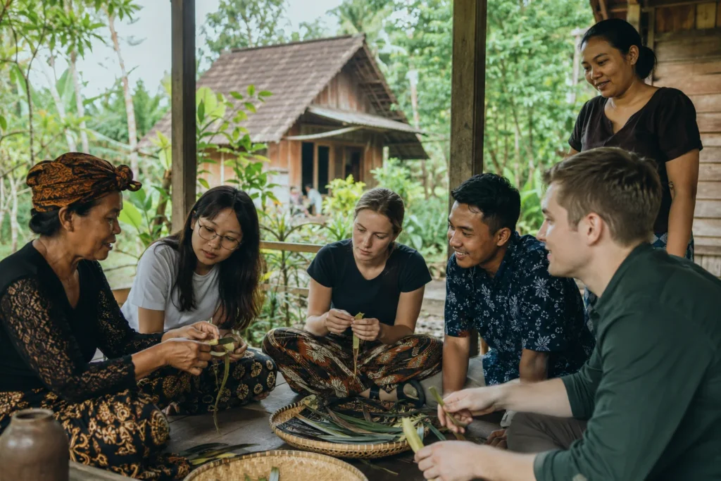 An Osing cultural host welcomes Indonesian and international young visitors in a Banyuwangi village courtyard.